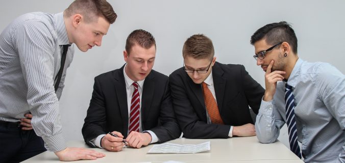 four men looking to the paper on table